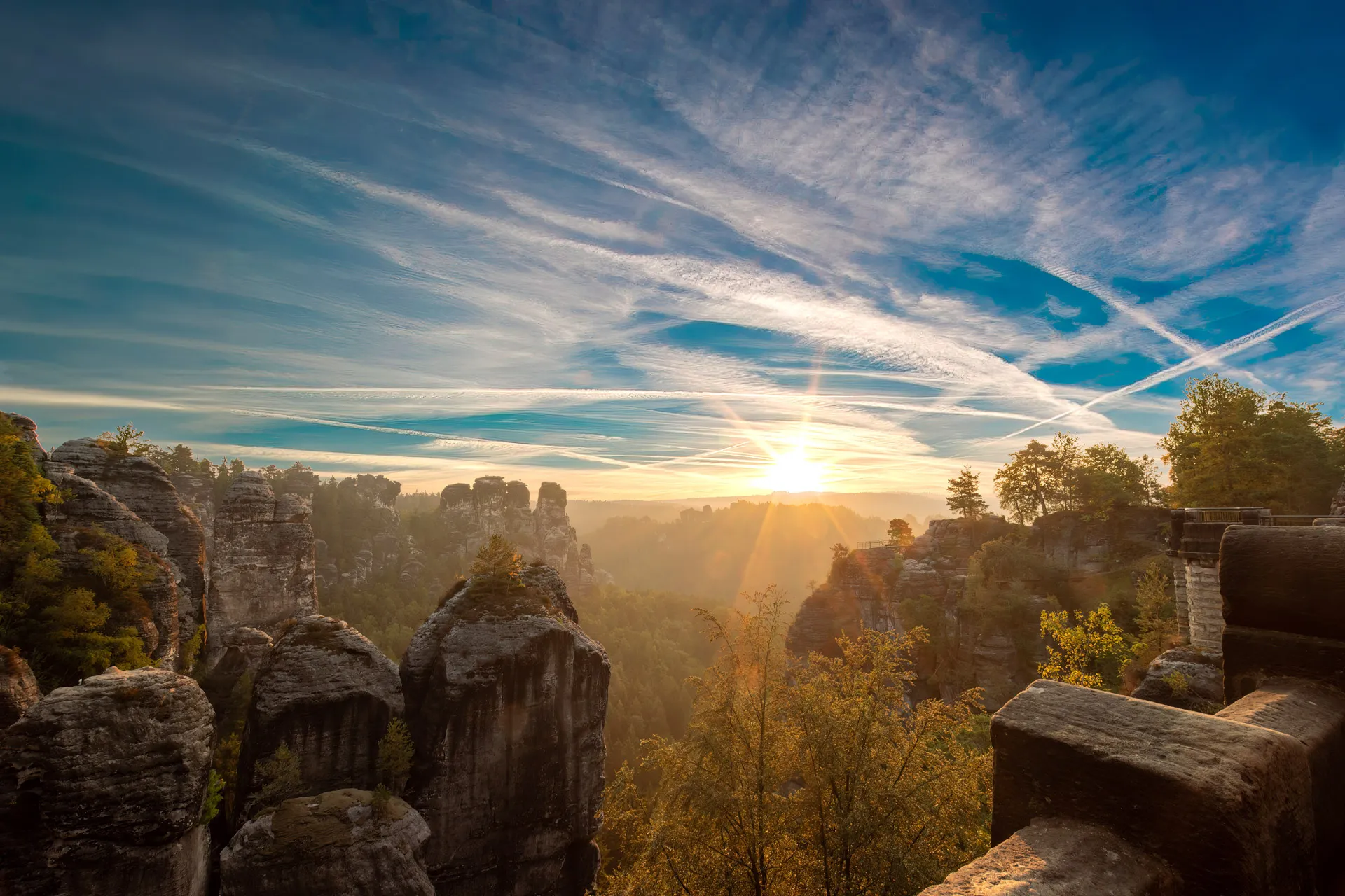 Sonnenaufgang zwischen den Felsnadeln der Bastei, der Himmel von Zirren durchzogen.