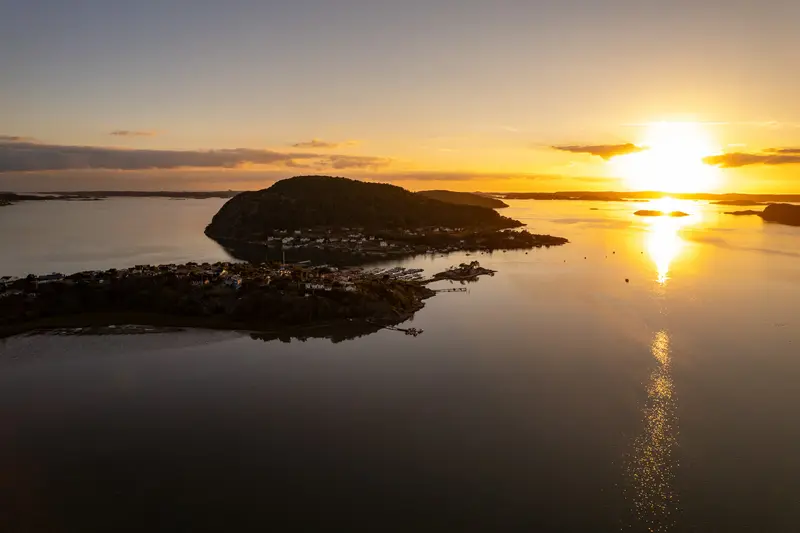 Sonnenuntergang über der Schärenküste von oben, eine Insel liegt im Gegenlicht.