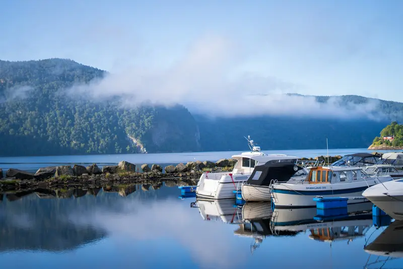 Boote im Hafen bei Nebel, die Bergflanke dahinter verschwindet im Dunst.