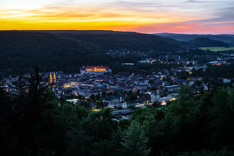 Blick über eine Stadt im Tal zur blauen Stunde, rosa Wolken darüber.