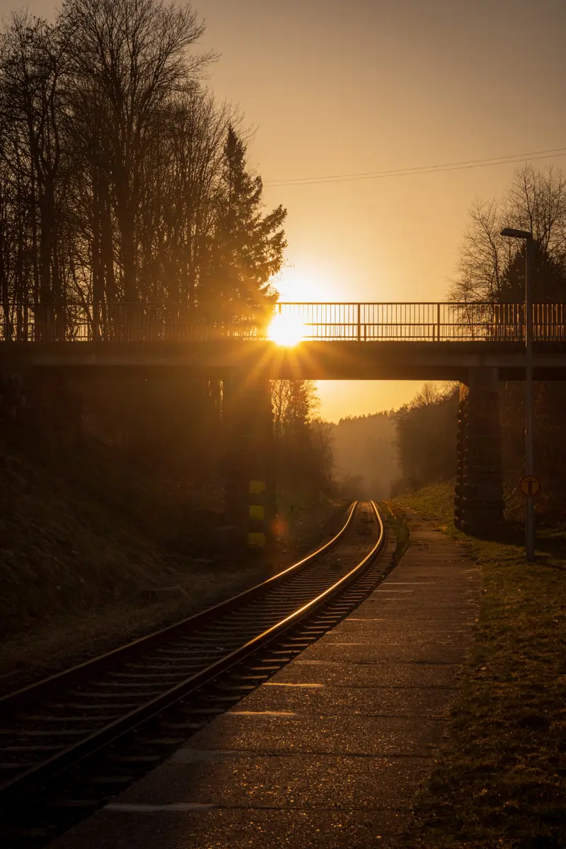 Gegenlicht unter einer Brücke, die Bahngleise führen ins Licht.
