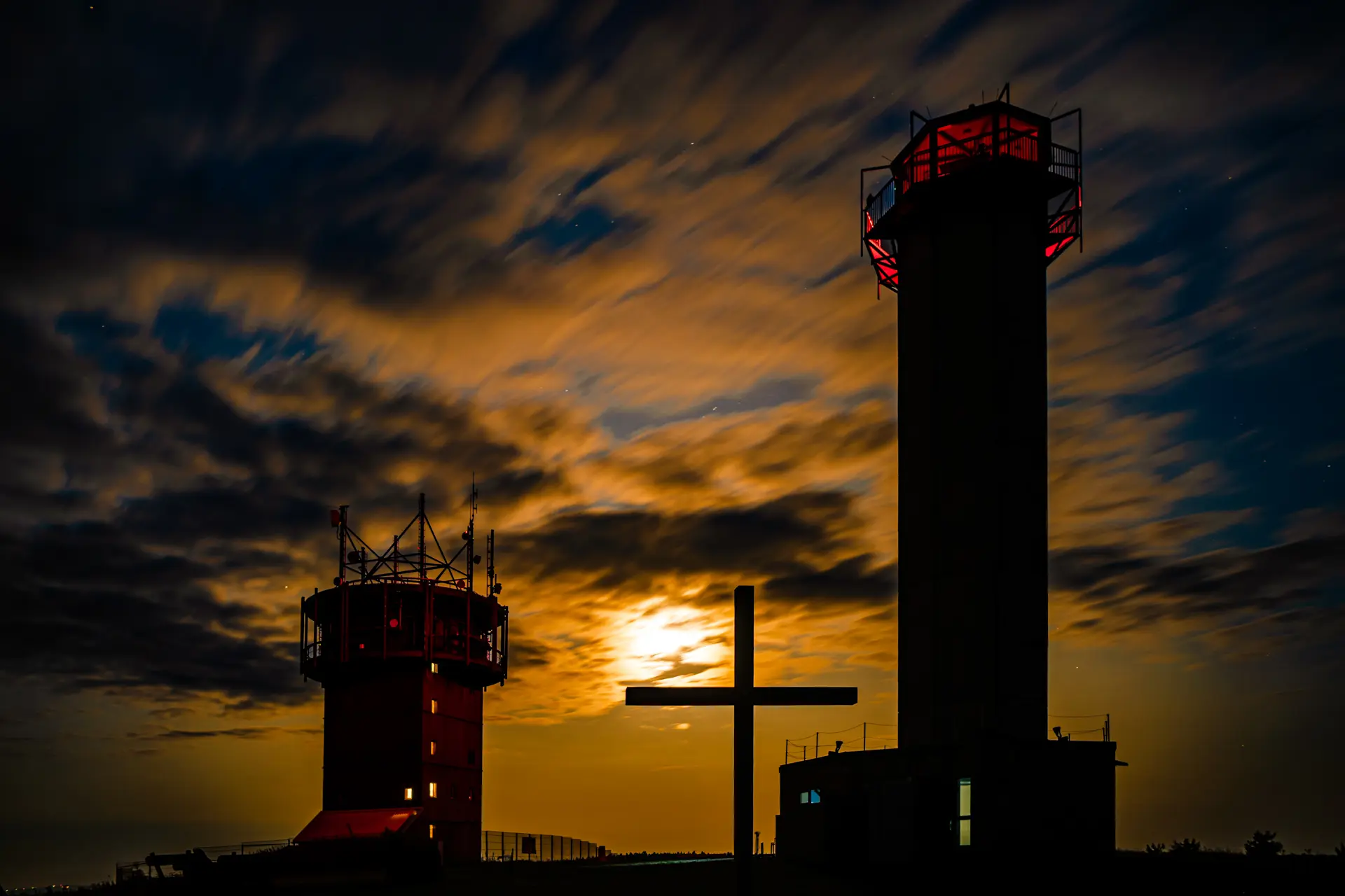 Schneekopf in Thüringen bei Sonnenuntergang mit Gipfelkreuz und Türmen